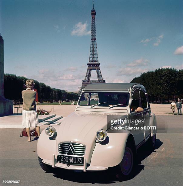 Citroën 2CV car in front of the Eiffel Tower in Paris, France, circa 1960 .