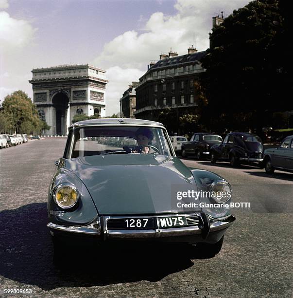 Citroën DS car in front of the Arc de Triomphe in Paris, France, circa 1960 .