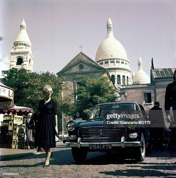 Peugeot 404 car in front of the Sacré-Coeur Basilica in Montmartre area in Paris, France, circa 1960 .