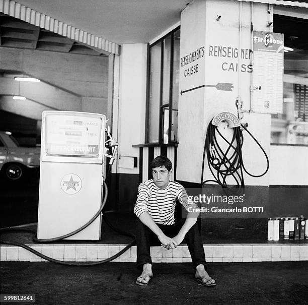Young man wearing striped jersey filling up at a gas station of Saint-Germain-des-Prés neighbourhood circa 1960 in Paris, France .