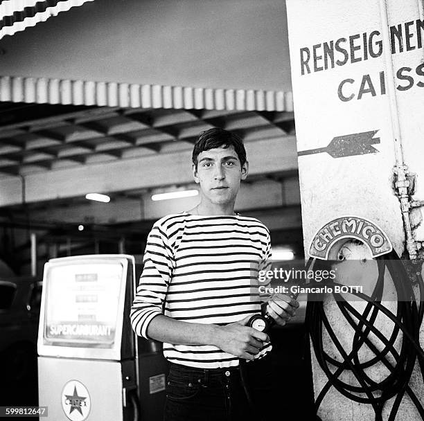 Young man wearing striped jersey filling up at a gas station of Saint-Germain-des-Prés neighbourhood circa 1960 in Paris, France .