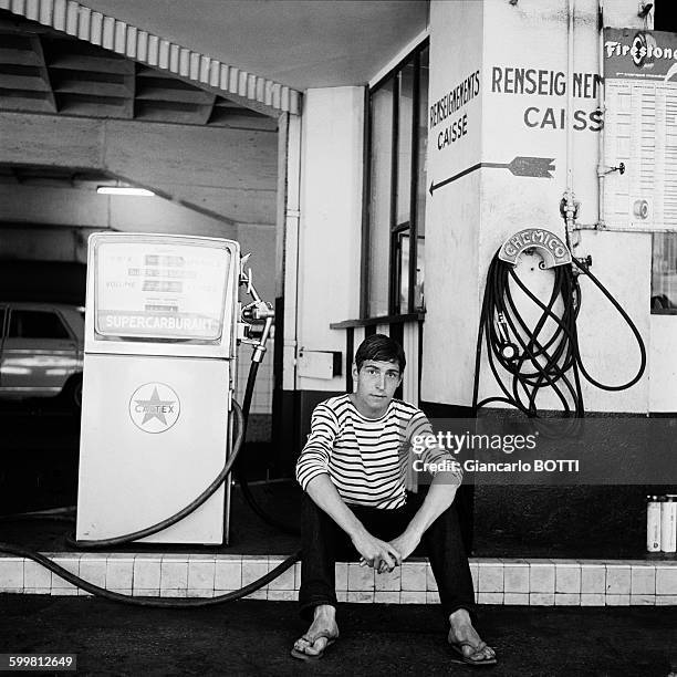 Young man wearing striped jersey filling up at a gas station of Saint-Germain-des-Prés neighbourhood circa 1960 in Paris, France .