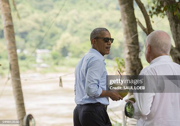 President Barack Obama holds a coconut to drink with US Ambassador to Laos Daniel Clune as he makes a surprise stop for a drink alongside the Mekong...