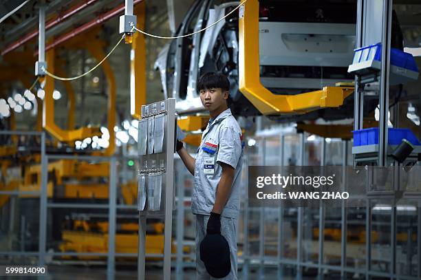 Worker watches the assembly line at DPCA Chengdu plant production start and Dongfeng Peugeot 4008 line in Chengdu on September 7, 2016. French auto...
