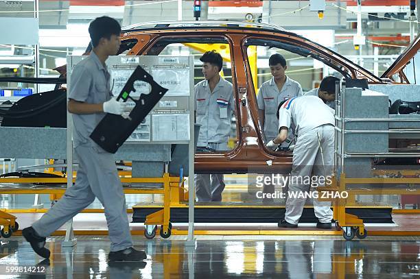 Chinese staff work on the assembly line at DPCA Chengdu plant production start and Dongfeng Peugeot 4008 line in Chengdu on September 7, 2016. French...
