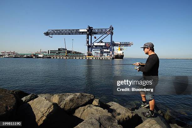 Man fishes as container ships sit berthed at the Port Botany container terminal in Sydney, Australia, on Tuesday, Sept. 6, 2016. Australia's annual...