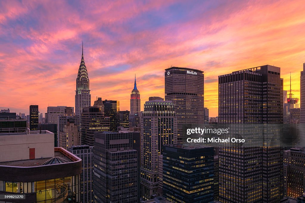 Beautiful colorful sunset over midtown Manhattan, viewed from a unique angle from a rooftop in NYC. Seeing the Empire State Building, Chrysler Building, MetLife Building.