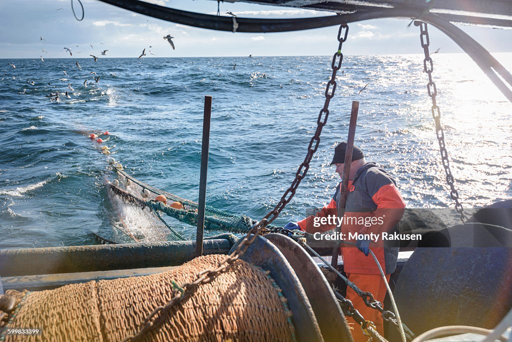 Fisherman tending nets on trawler