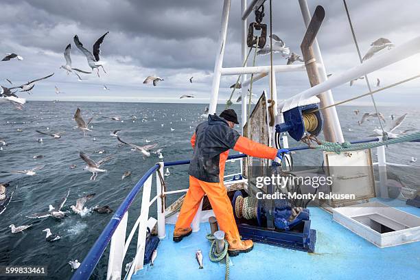 fisherman operating winch on deck of trawler - fishing boat 個照片及圖片檔