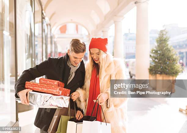 young couple looking at xmas gifts in covent garden, london, uk - fur coat stockfoto's en -beelden