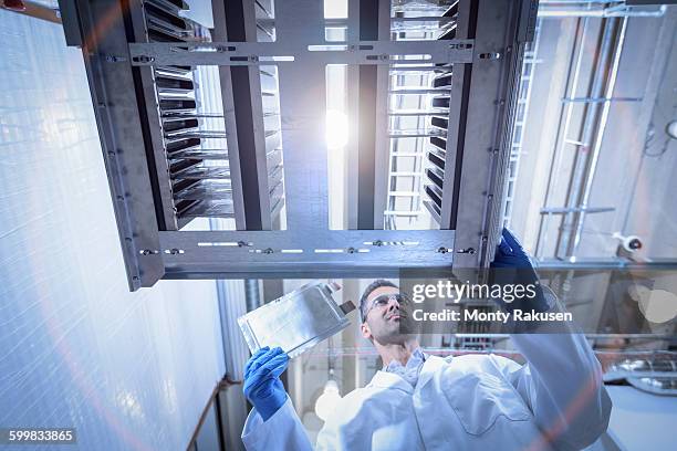 scientist with lithium ion pouch cell manufacture machine in battery research facility, low angle view - lithium ion battery stock pictures, royalty-free photos & images