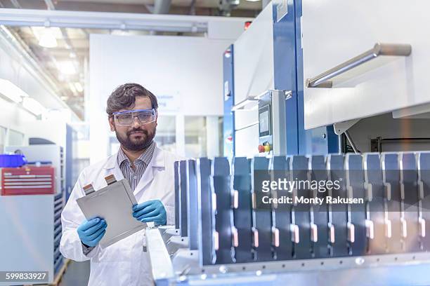 scientist with lithium ion pouch cell manufacture machine in battery research facility - lithium ion battery stock pictures, royalty-free photos & images