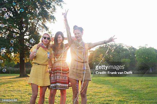 portrait of three young women friends wrapping themselves in streamers at party in park - young women only stock-fotos und bilder