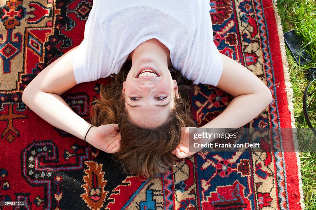 Overhead view of young woman lying back on rug