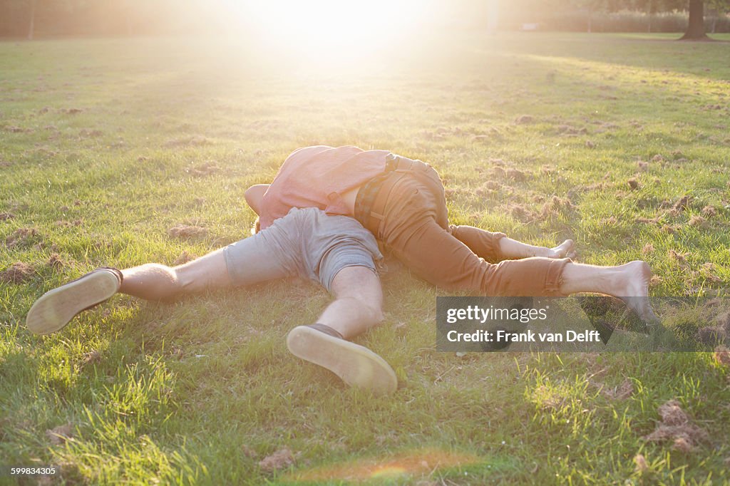 Two young men play fighting on park grass