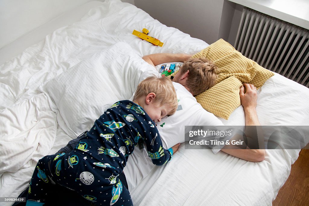 Young boy lying on top of father n bed