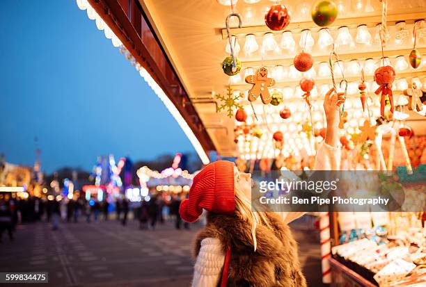 young woman choosing baubles at xmas festival in hyde park, london, uk - christmas market decoration stockfoto's en -beelden