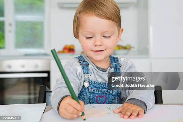 female toddler drawing at kitchen table - colorare foto e immagini stock