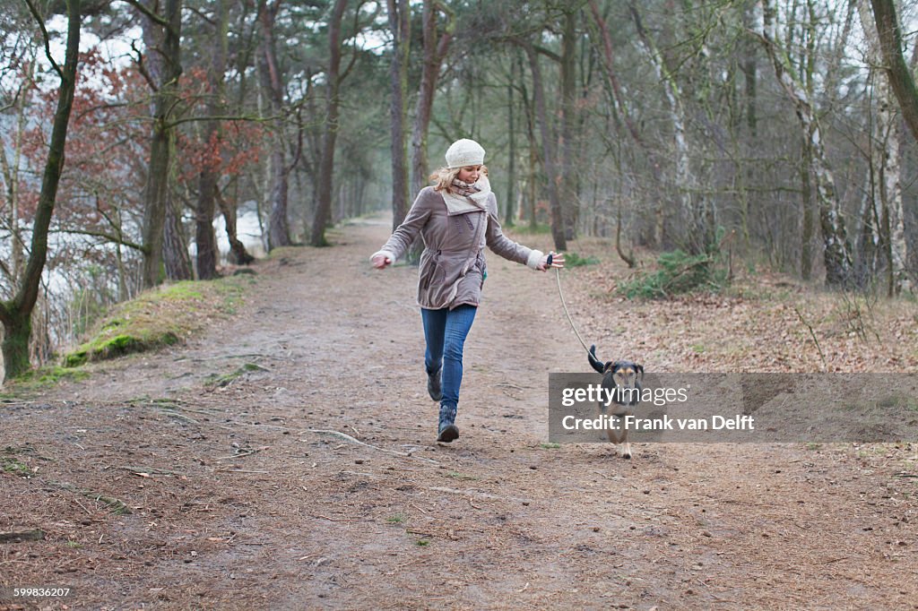 Mid adult woman running with her dog in forest