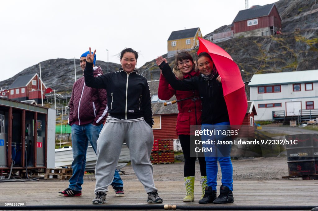Teenage school students and their teacher wave goodbye from a dock on an arctic island.