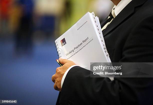 Mike Ashley, billionaire and founder of Sports Direct International Plc, holds a copy of working practices report prior to the company's annual...