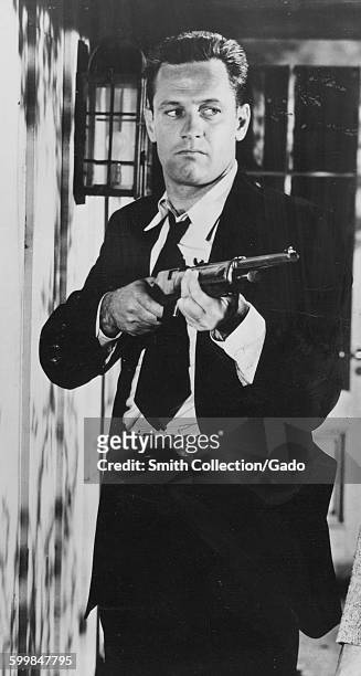 William Holden with a rifle in a movie still, 1950.