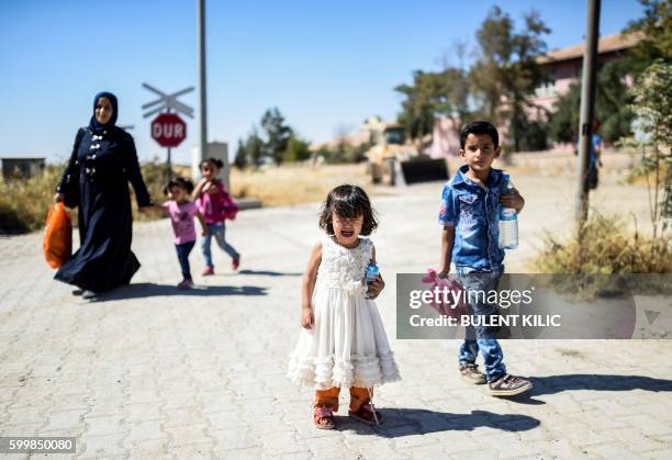 Syrian refugees walk on their way back to the Syrian city of Jarabulus on September 7, 2016 at Karkamis crossing gate, in the southern region of...