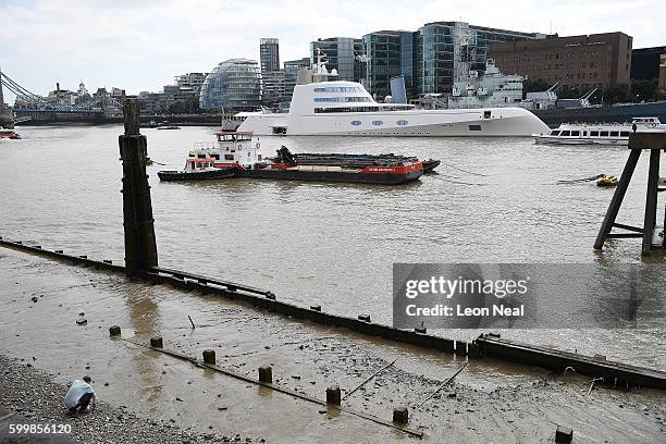 Man walks on the pebble shore as Russian billionaire Andrey Melnichenko's £225m Philippe Starck-designed boat is seen moored next to HMS Belfast on...