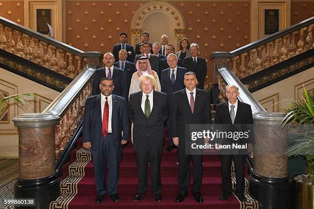 Britain's Foreign Secretary Boris Johnson and Chief Negotiator for the Syrian Opposition Dr Riyad Hijab stand with members of the Syrian High...