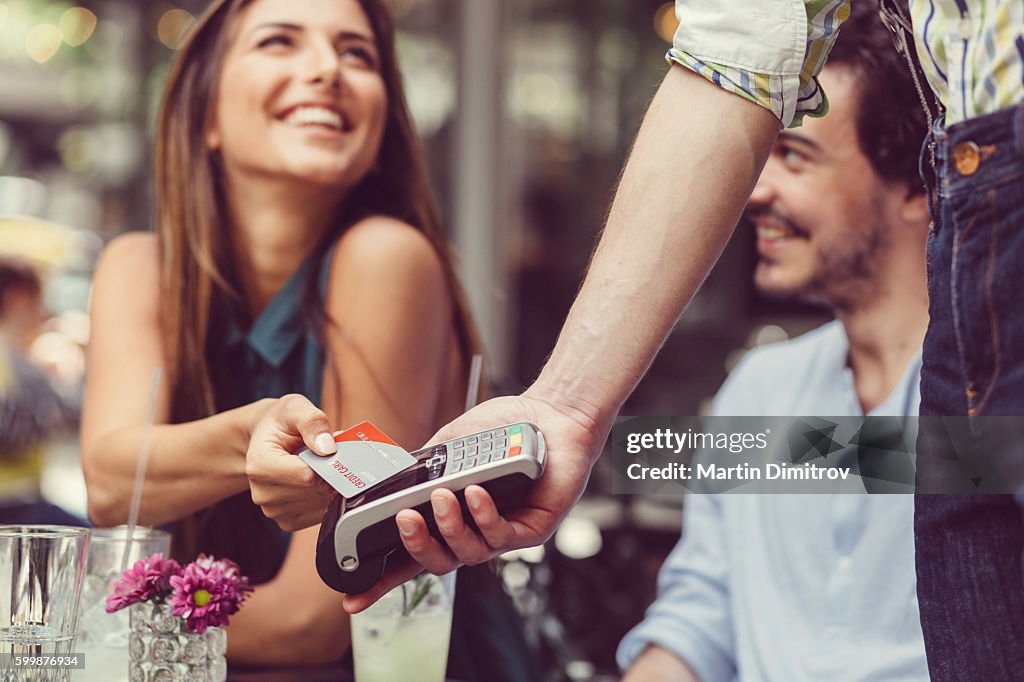 Woman in a cafe making contactless credit card payment