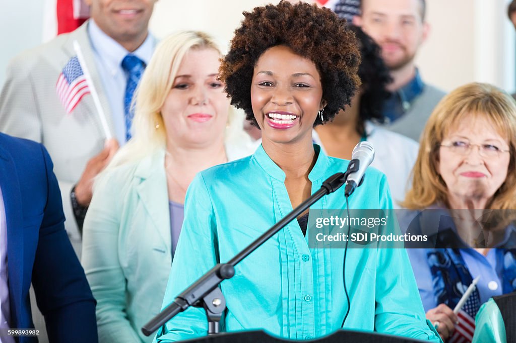 Woman smiling while speaking at local political rally or event