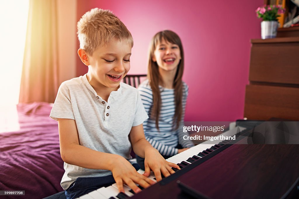 Brother and sister playing piano together