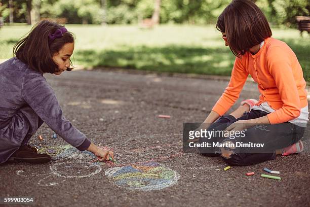 kids drawing with chalk on asphalt - chalk art equipment stock pictures, royalty-free photos & images
