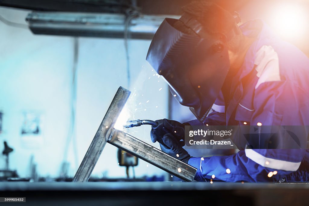 Welder in factory welding steel construction for new machine