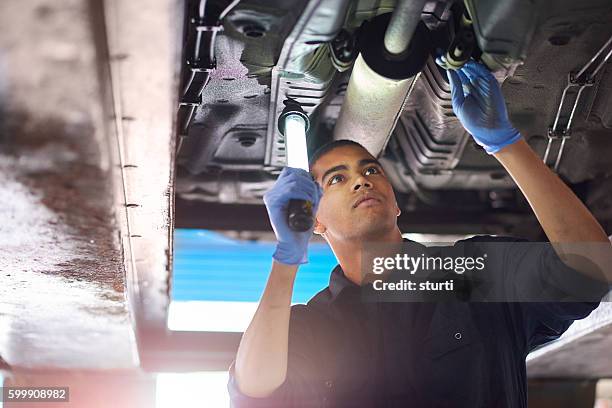 mechanic checks exhaust - reparatiewerkplaats stockfoto's en -beelden