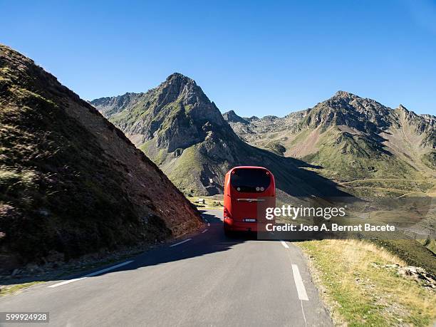 bus circulating a downhill mountain road in the pyrenees - pirineos fotografías e imágenes de stock