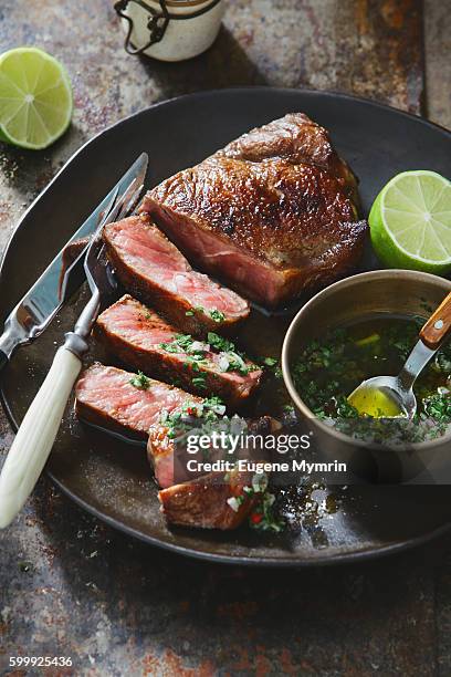 strip steak with chimichurri sauce - steak stock-fotos und bilder