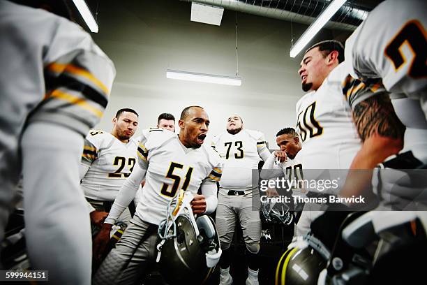 football player leading team motivational chant - locker room photos et images de collection