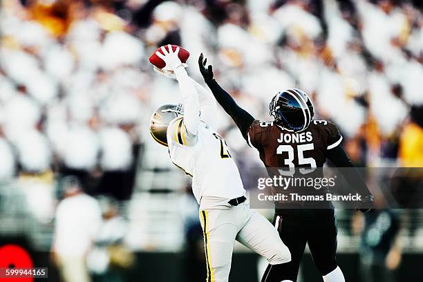 football receiver leaping over defender for catch - försvarare fotbollsspelare bildbanksfoton och bilder