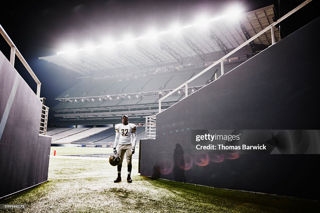 Football player standing at end of stadium tunnel