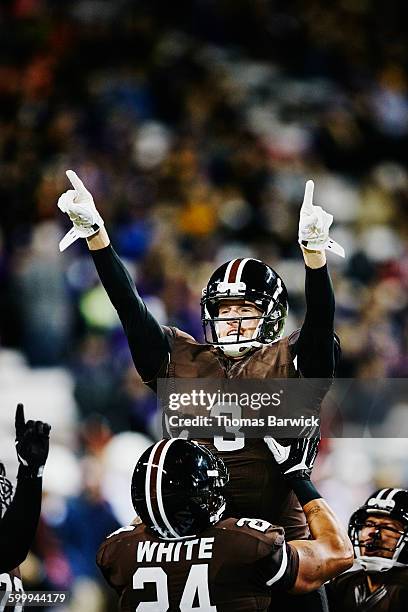 football player lifting quarterback in air - quaterbacks stockfoto's en -beelden