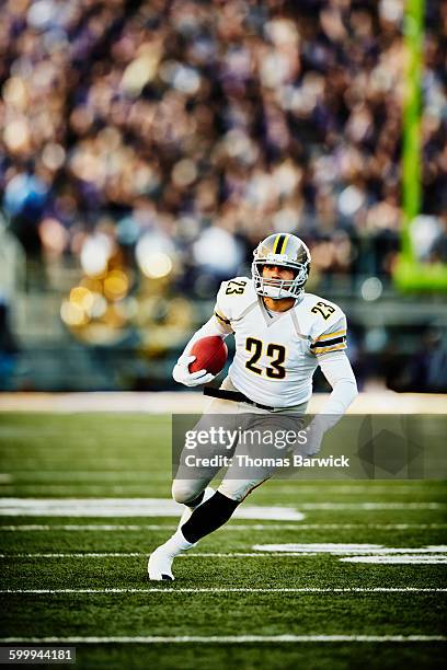 football running back with ball running downfield - football spieler stock-fotos und bilder