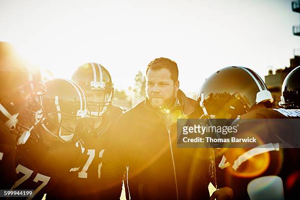 football coach in discussion with players on field - american football coach stock-fotos und bilder
