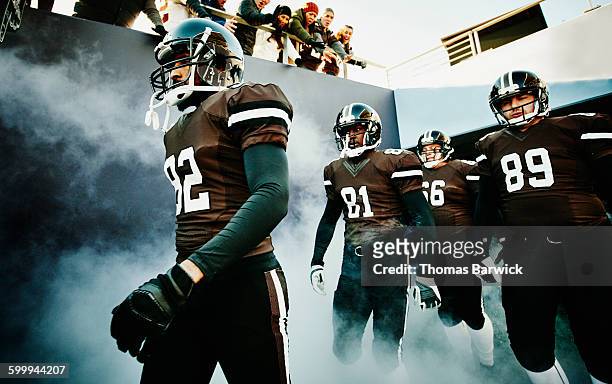 football team walking out of stadium tunnel - american football sport stock-fotos und bilder