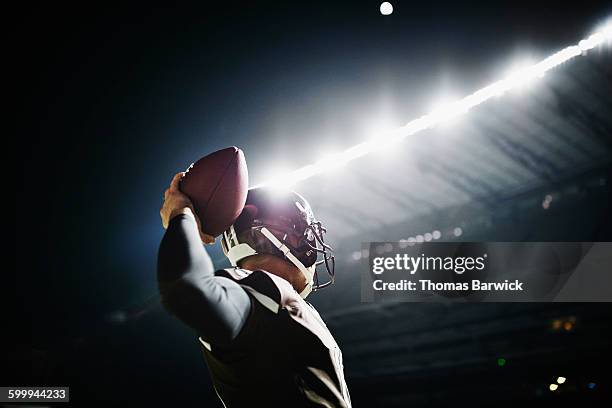 quarterback preparing to throw pass at night - football helmet stock-fotos und bilder
