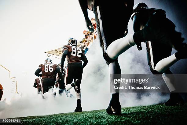 football team running out of tunnel onto field - rush american football stockfoto's en -beelden