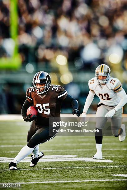 football running back carrying ball downfield - rush american football stockfoto's en -beelden