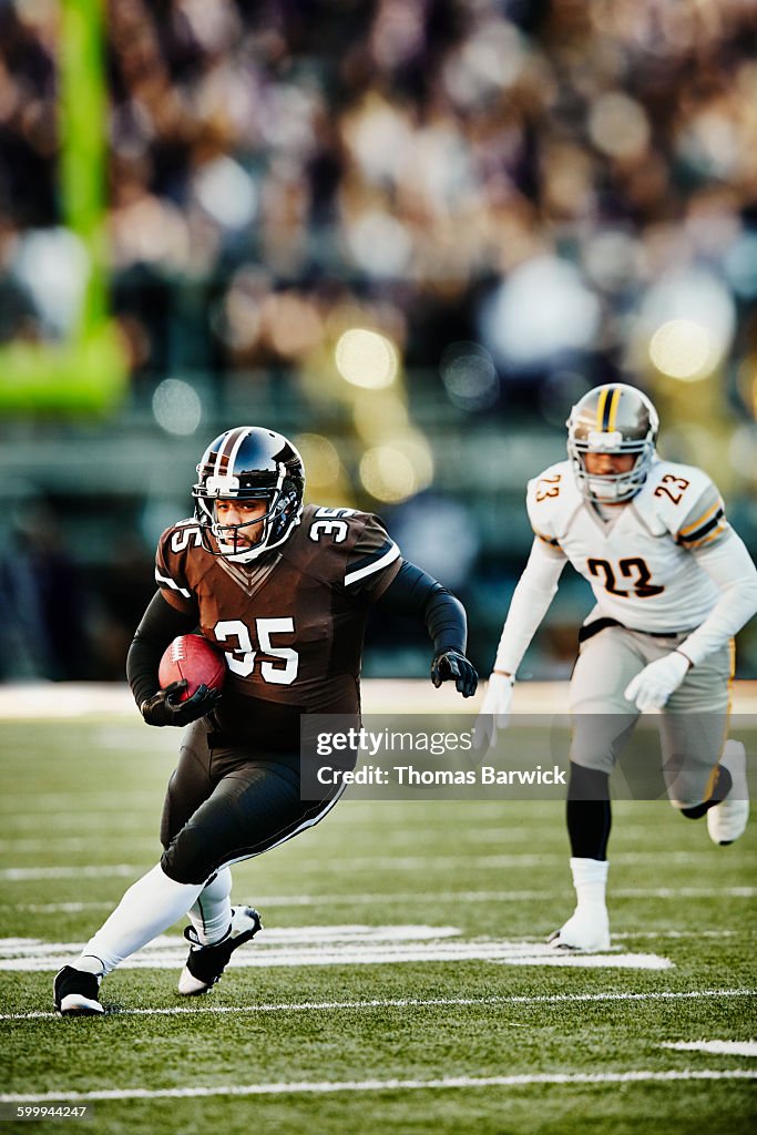 Football running back carrying ball downfield