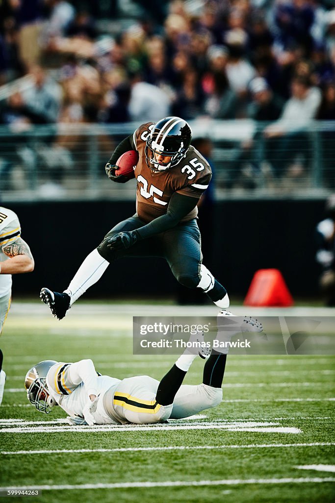 Football running back leaping over tackler