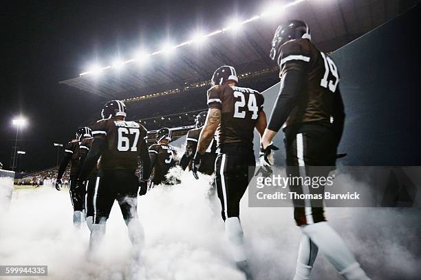football team walking out of stadium tunnel - american football stock pictures, royalty-free photos & images